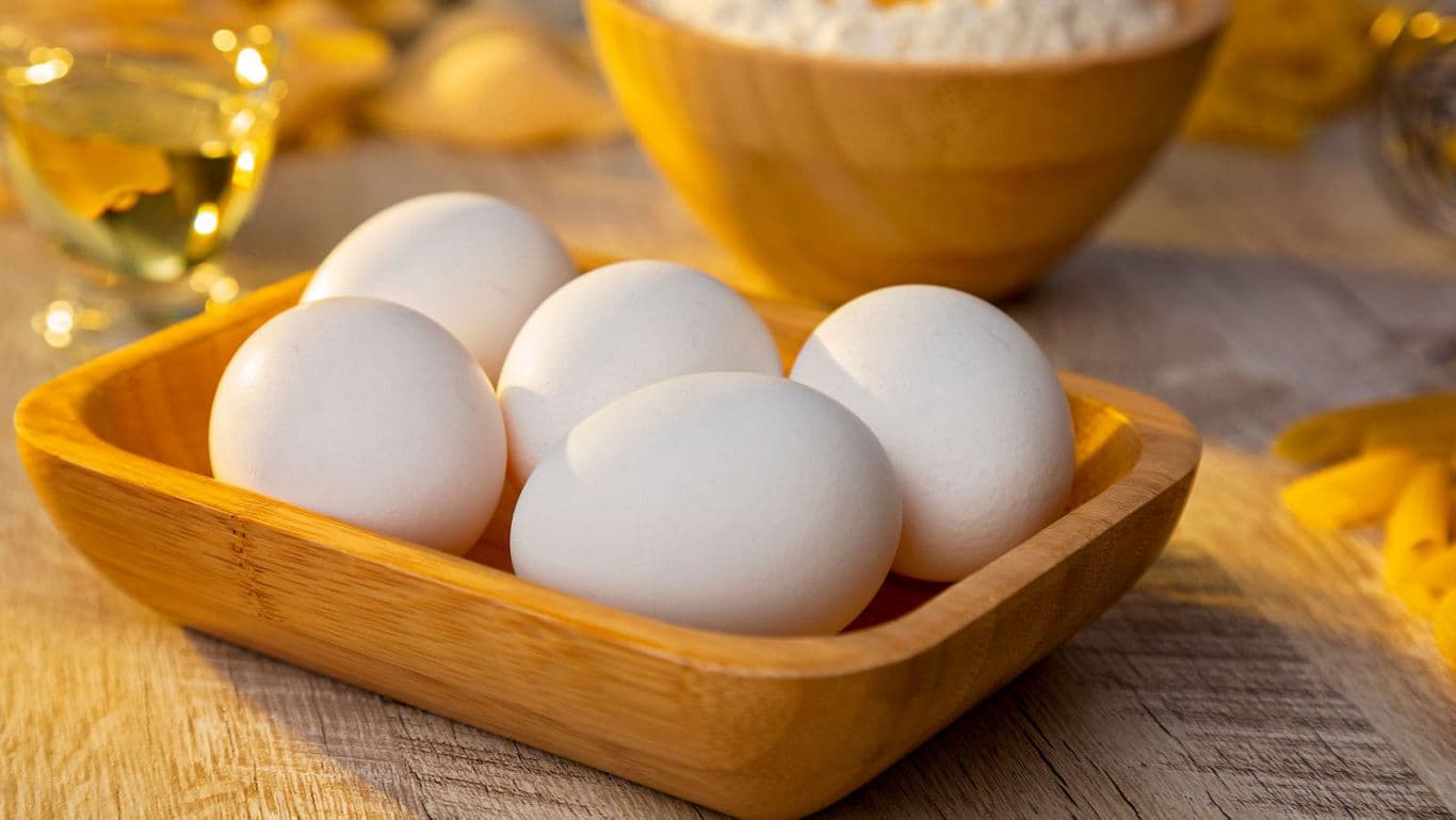 Fresh white eggs in wooden tray