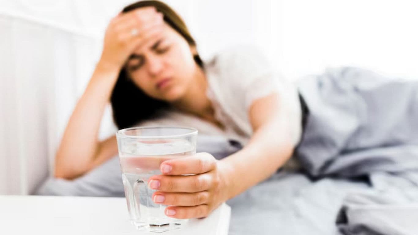 Woman holding glass of water in bed