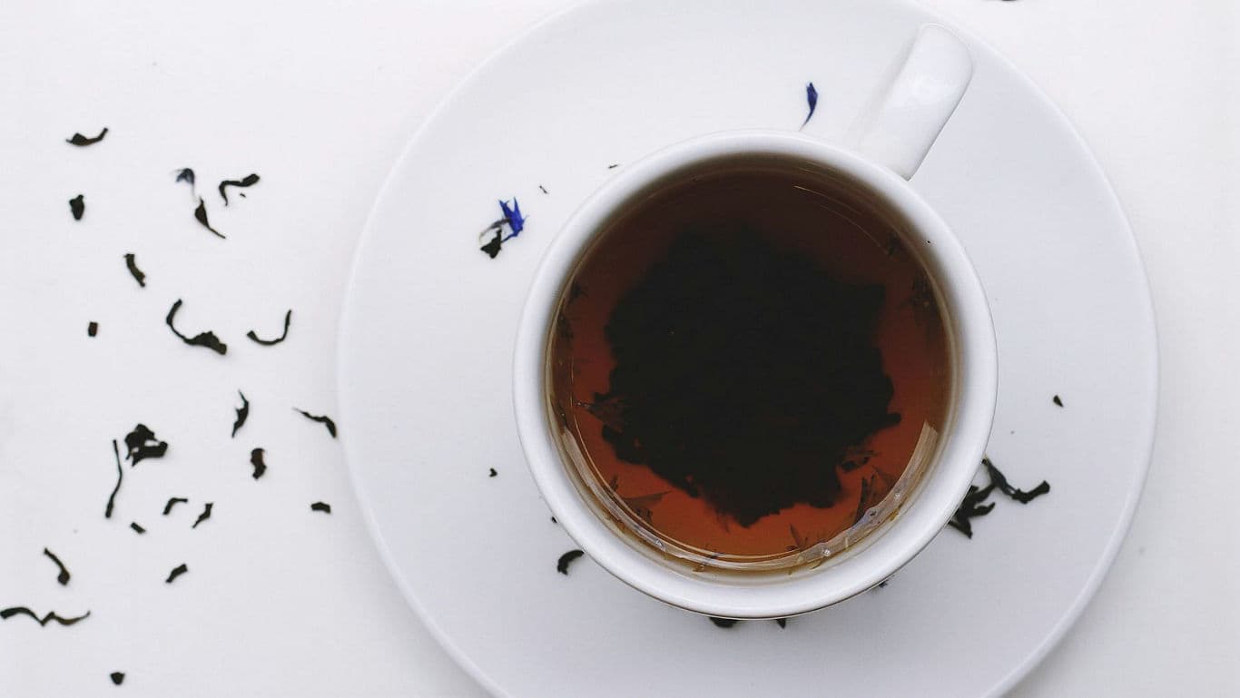 Cup of black tea with loose leaves