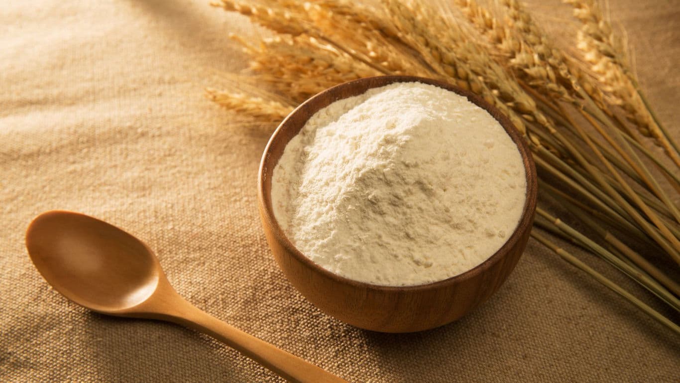 Wooden bowl of flour with wheat stalks