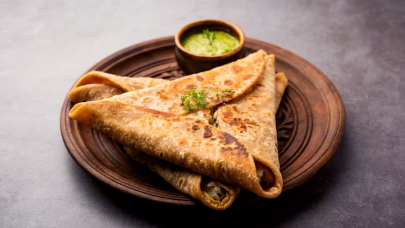 Stuffed paratha served with green chutney on plate