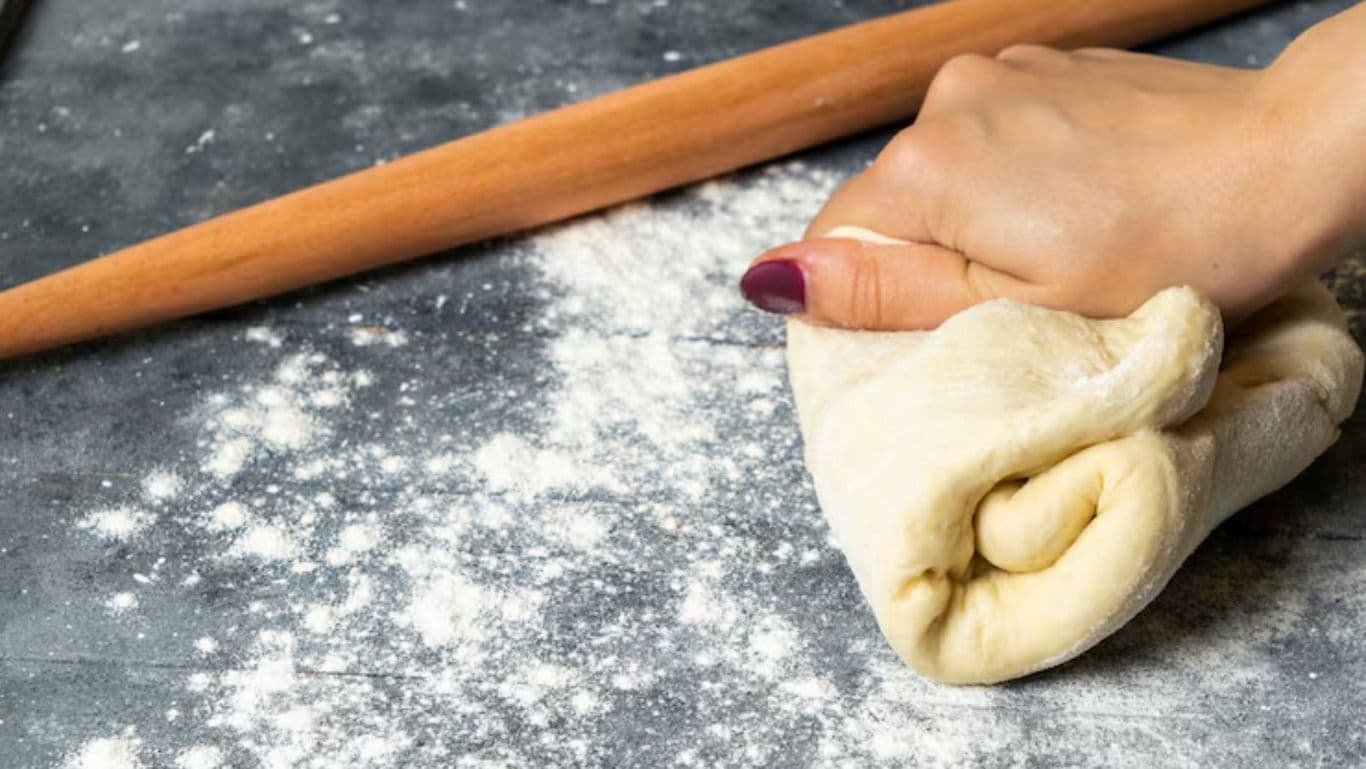Hand kneading dough with rolling pin nearby