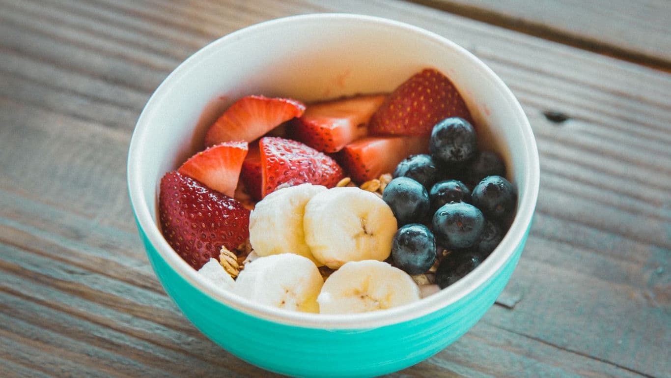 Fresh fruit and granola breakfast bowl on wood table