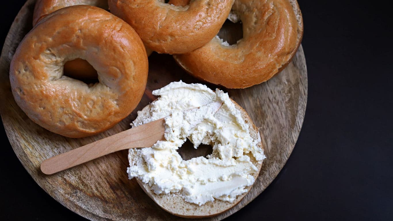 Fresh bagels with cream cheese on board