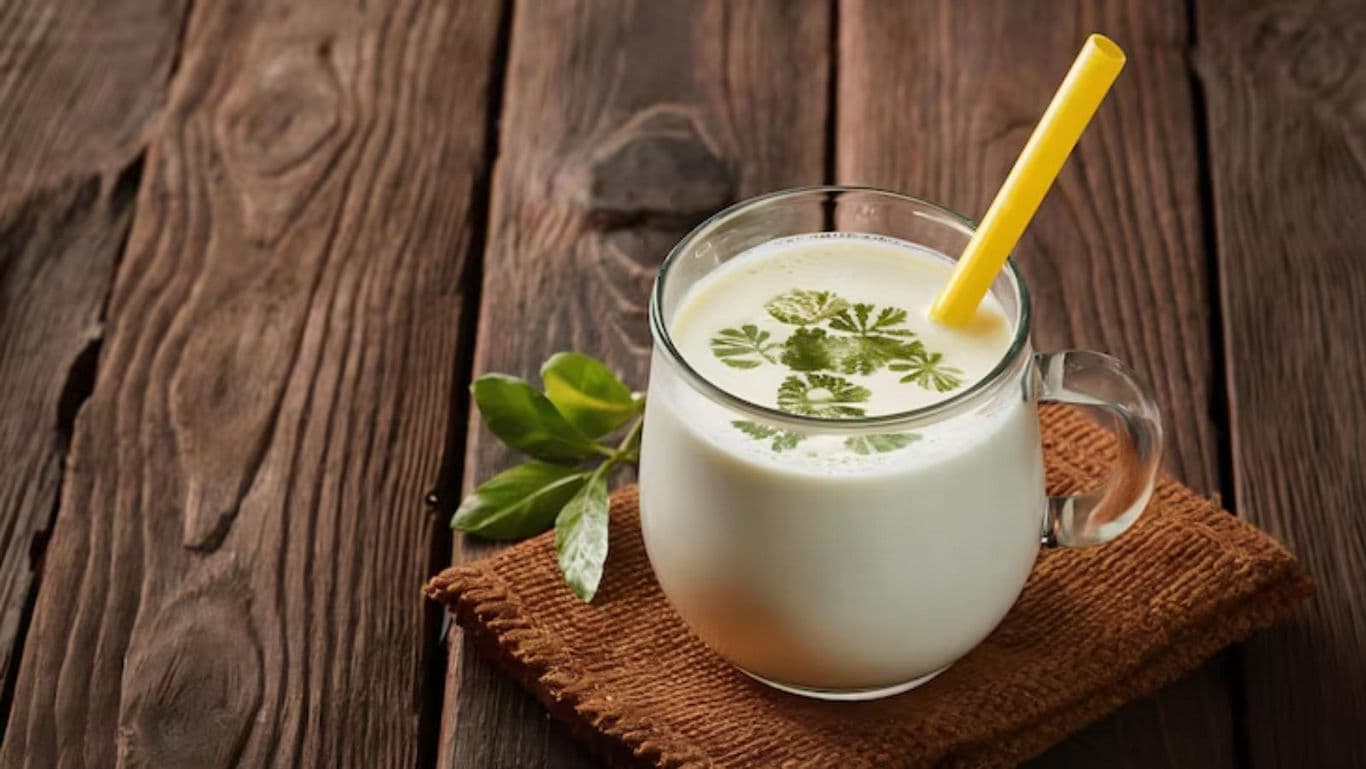 Glass of buttermilk with herbs on wooden table