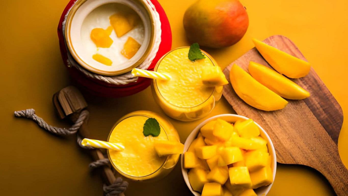 Fresh Mango Smoothie and Slices on Yellow Table