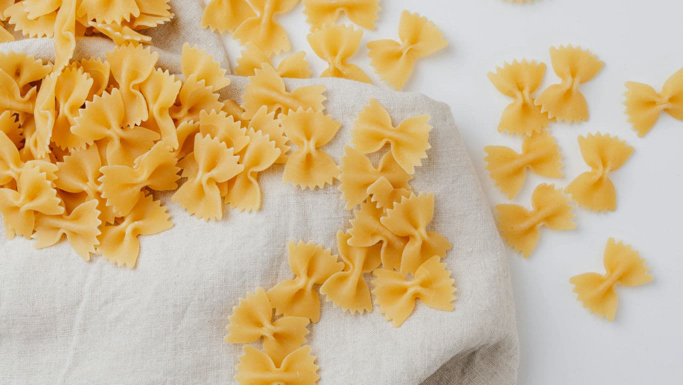 Uncooked farfalle pasta scattered on cloth