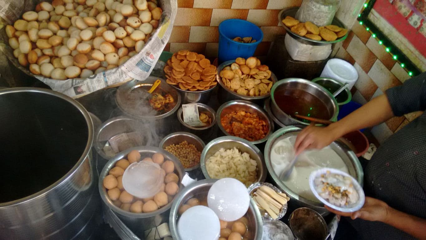 Street vendor preparing Indian chaat with assorted ingredients