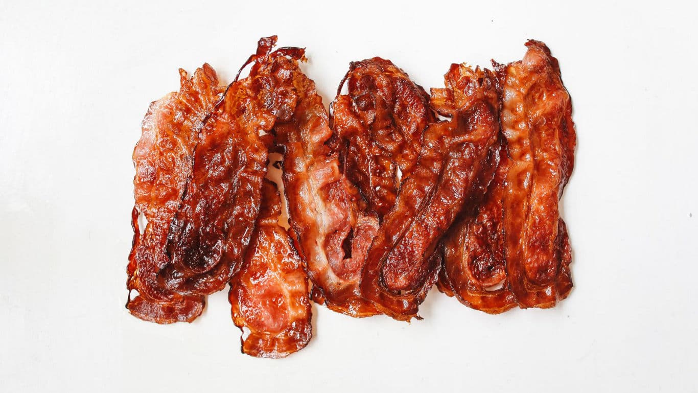 Crispy cooked bacon strips on white background