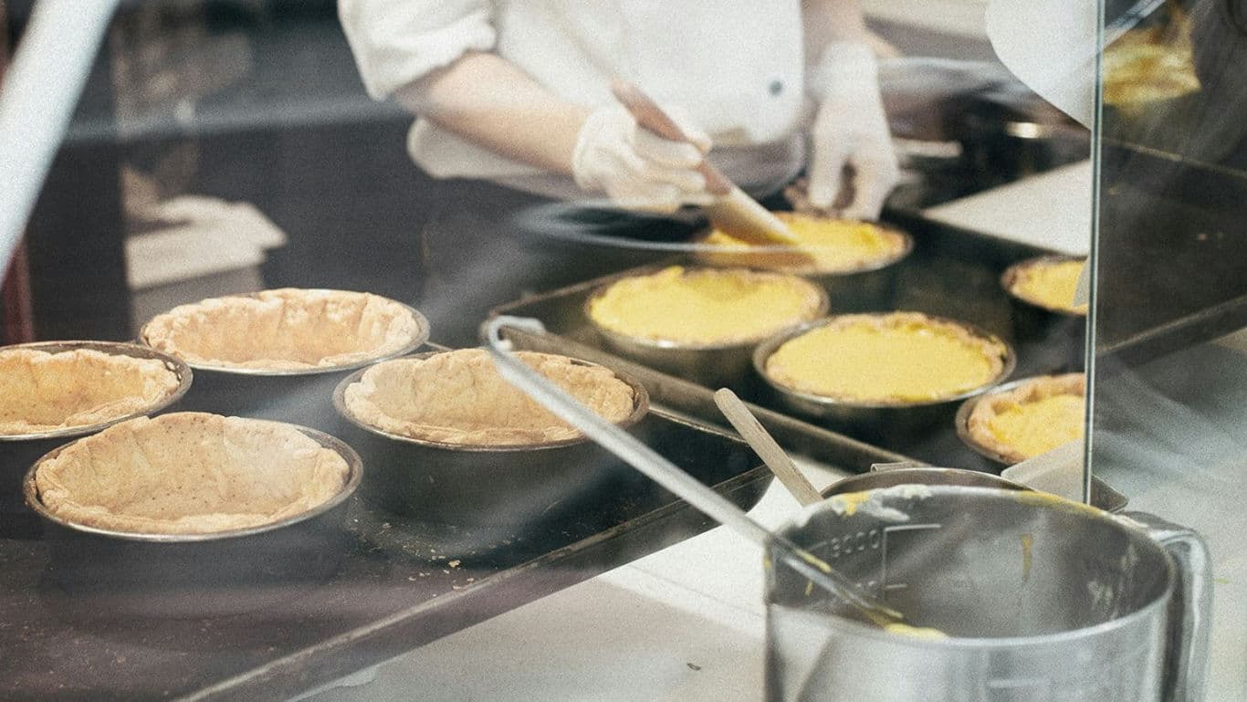 Pastry chef filling multiple pie crusts