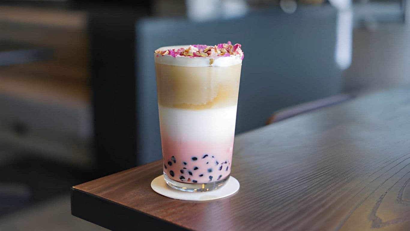 Layered bubble tea with rose petals on table