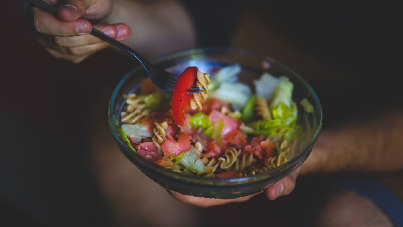 Fresh salad bowl with fork in hand