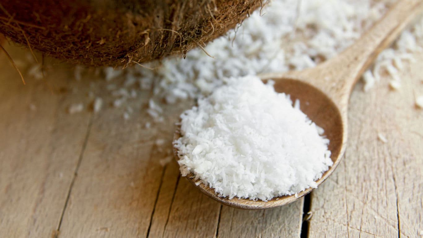 Shredded coconut in wooden spoon closeup