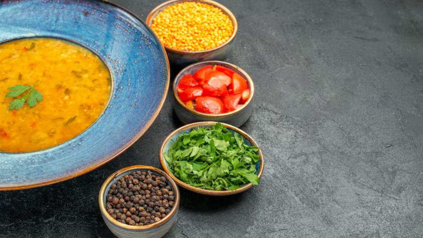 Lentil soup with fresh ingredients displayed