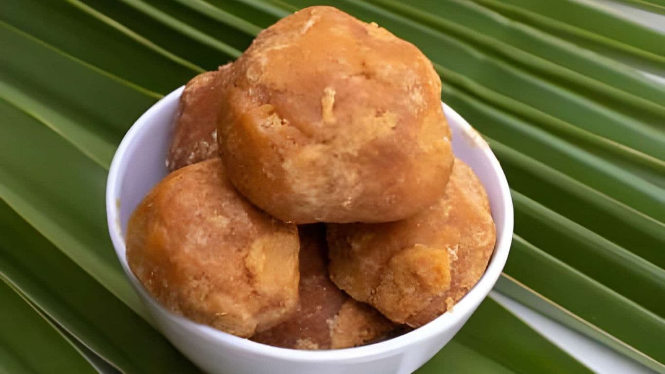 Bowl of traditional brown jaggery balls on leaves