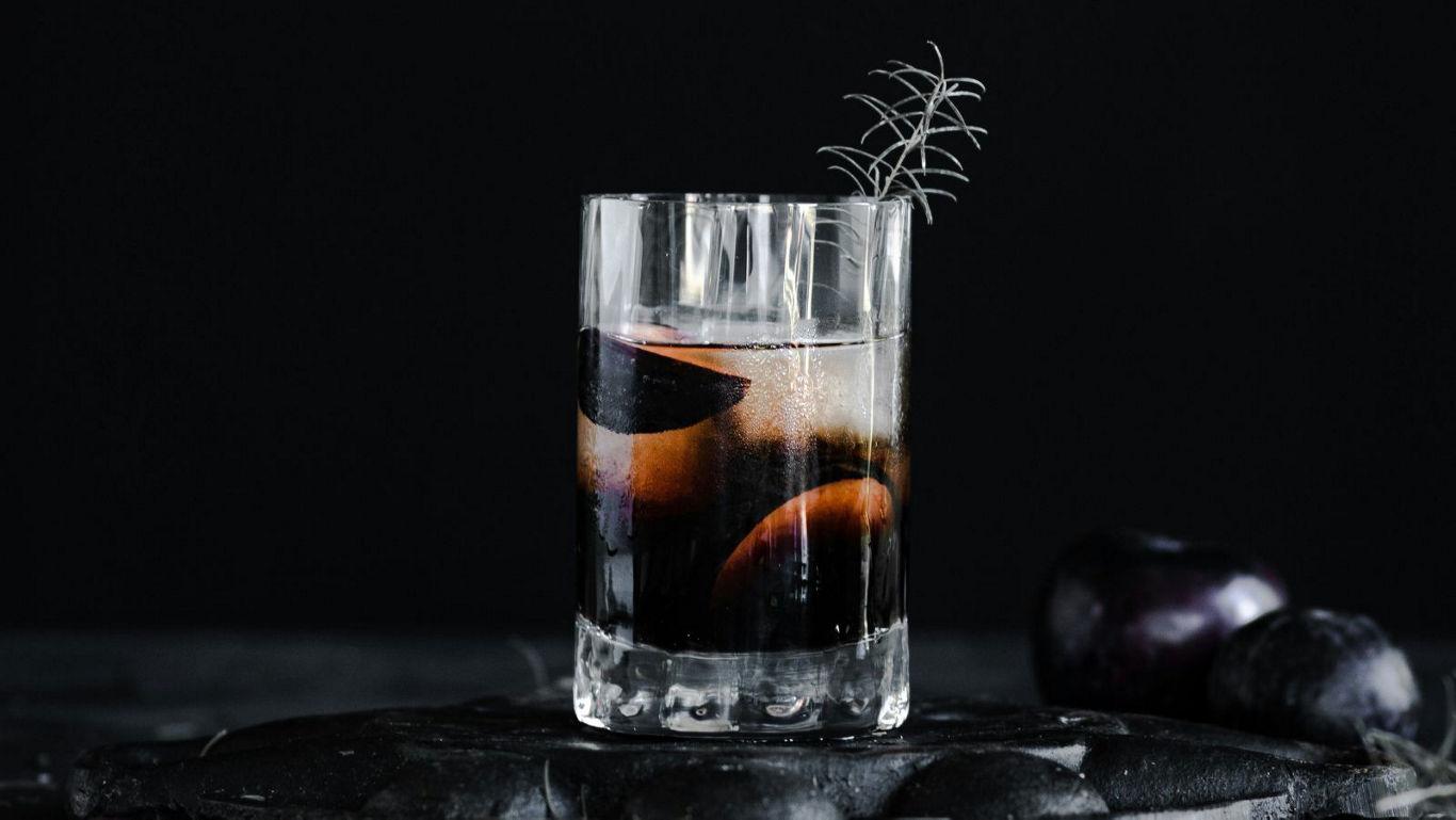 Dark plum cocktail with rosemary garnish