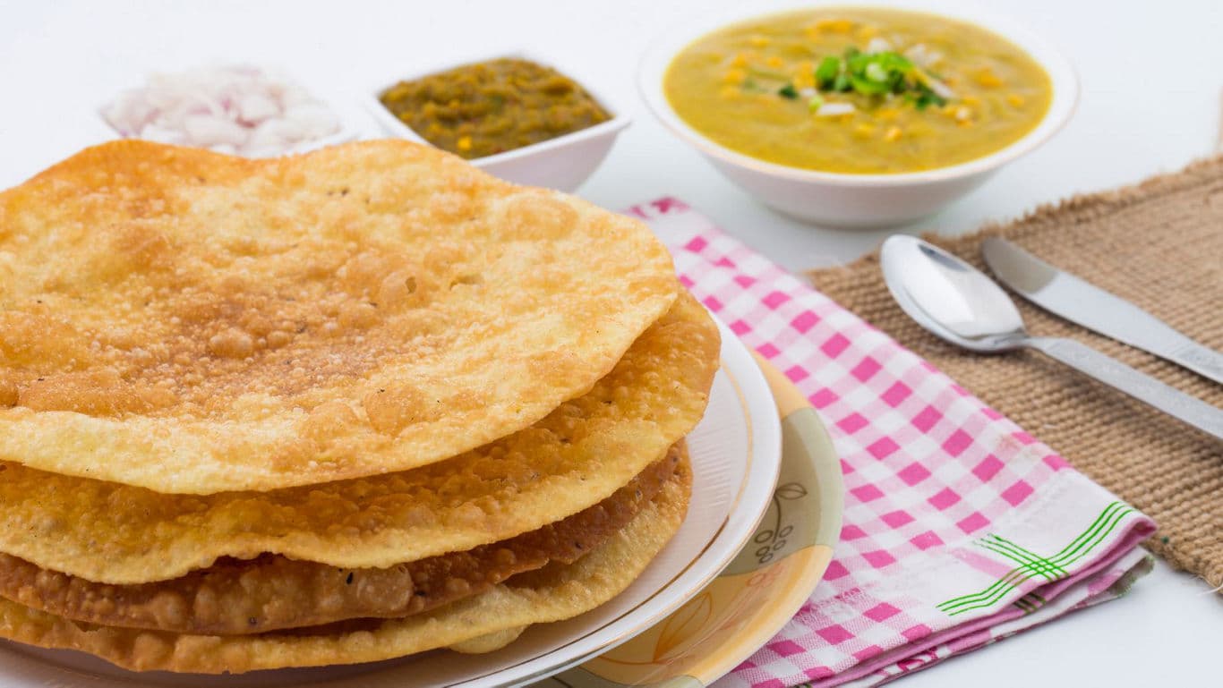 Crispy puris served with dal and chutney sides