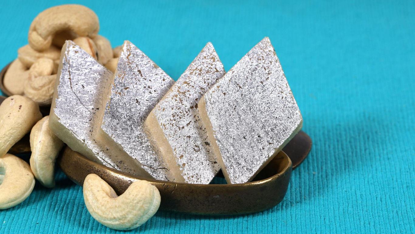 Silver-coated sweets with cashews on teal