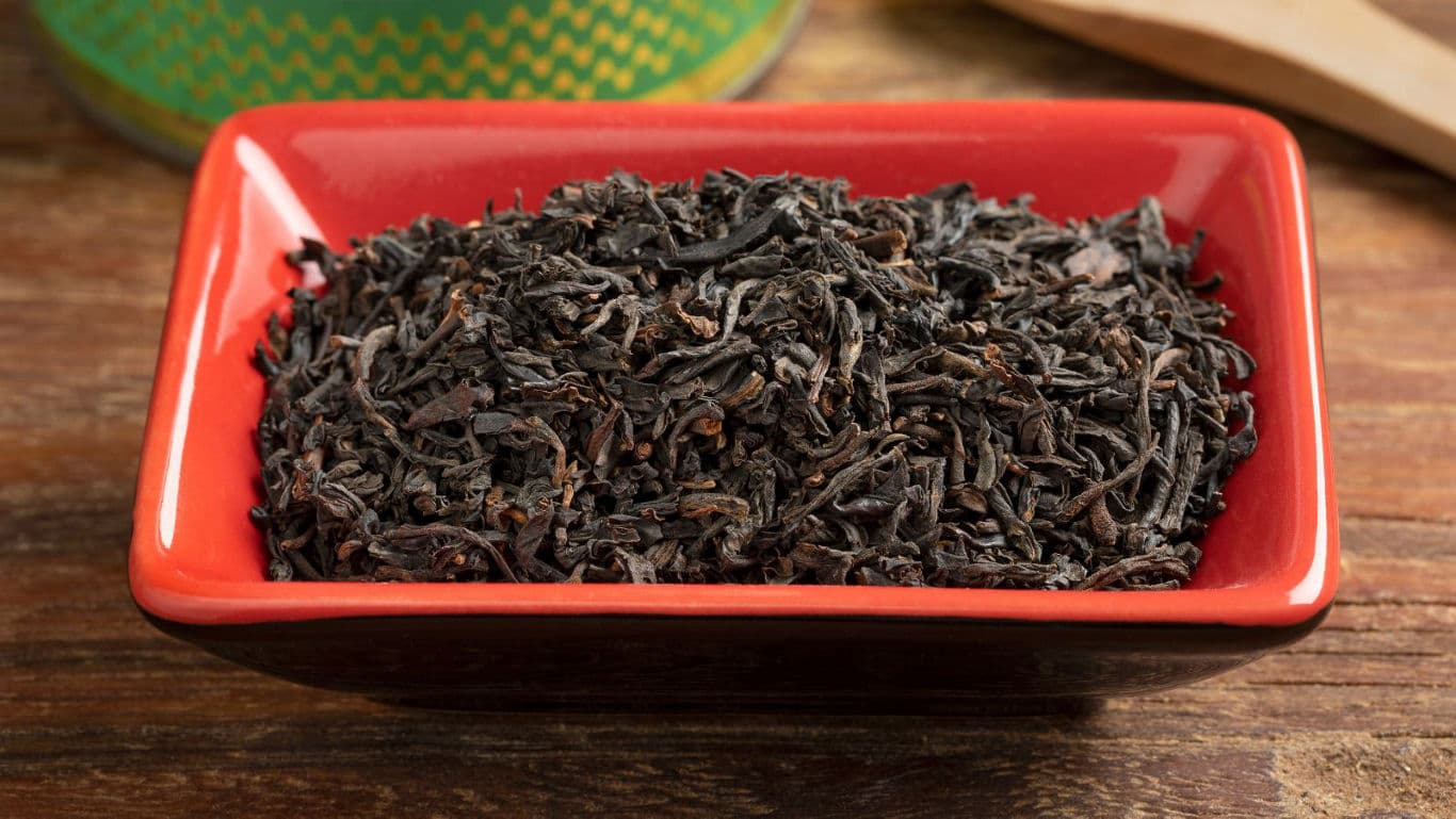 Loose black tea leaves in red dish