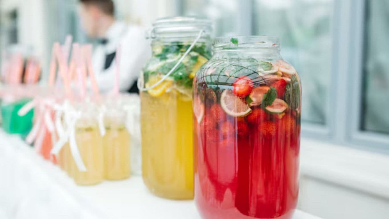 Large glass jars with colorful fruit beverages at event
