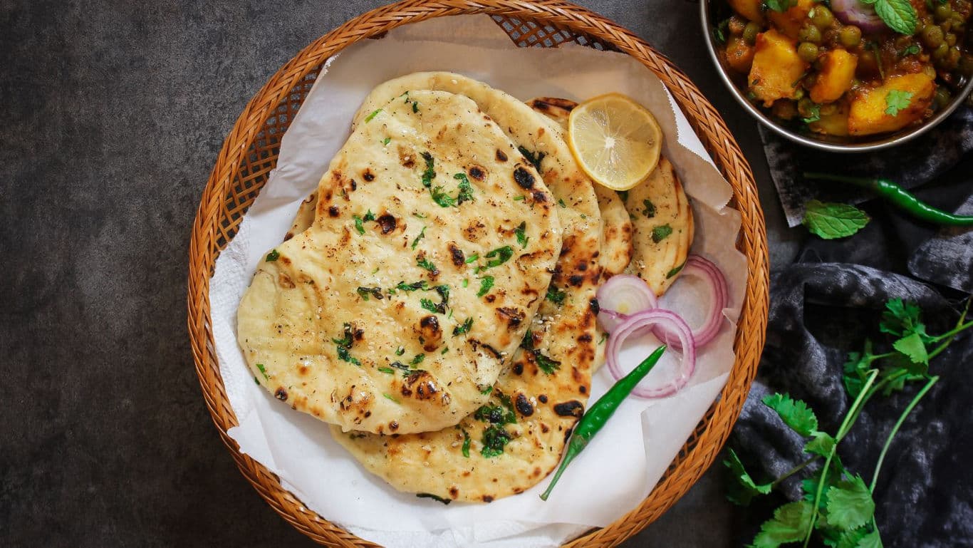Basket of naan bread with garnishes