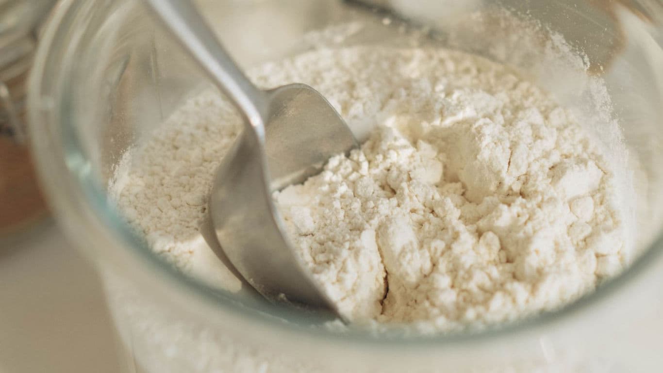 Glass jar of flour with metal scoop