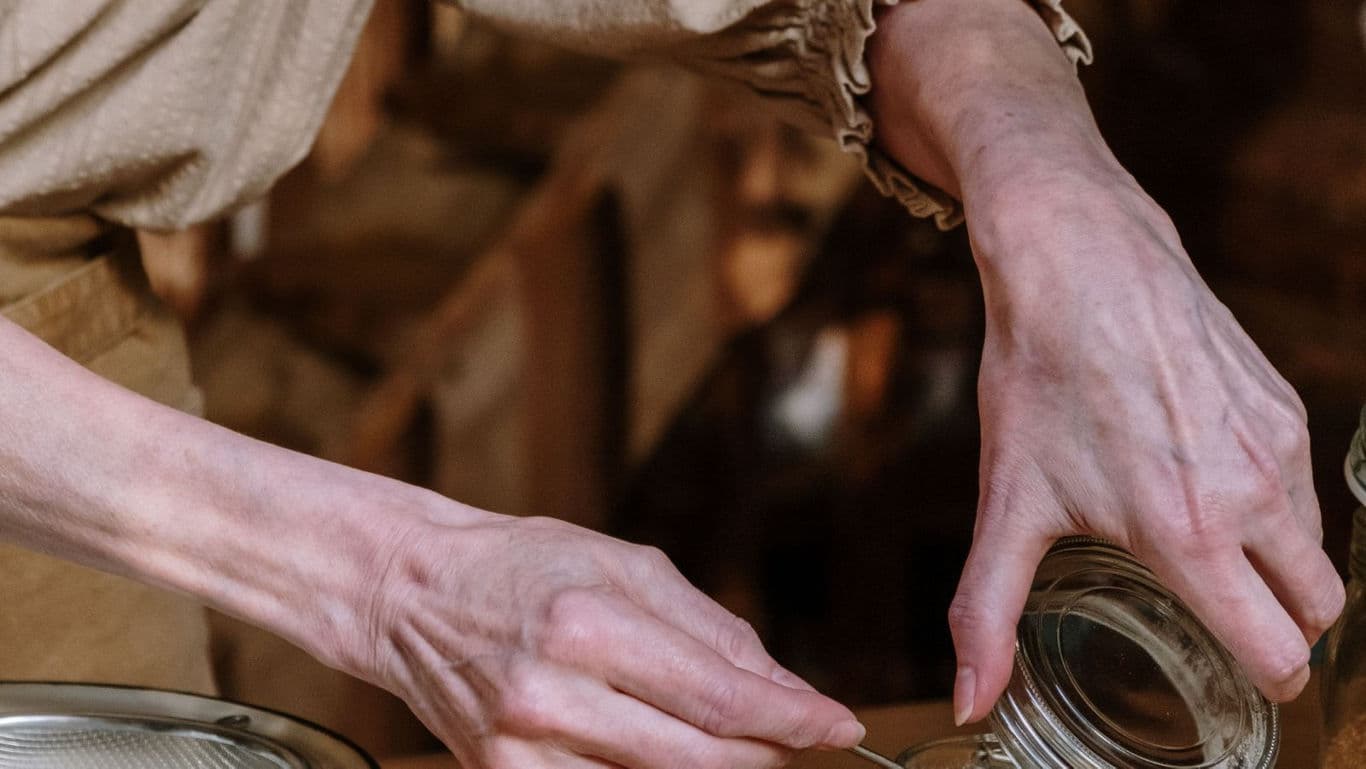 Hands pouring ingredients into glass jar