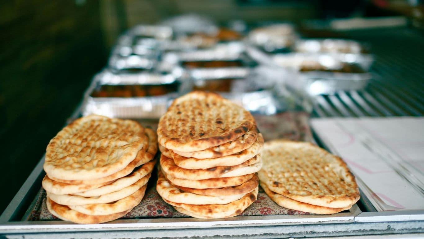 Stacked flatbreads on metal bakery counter