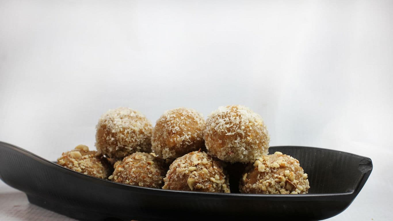 Nut-coated dessert balls on black serving dish