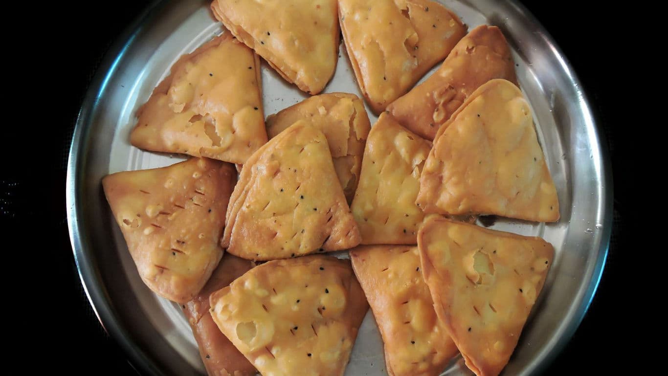 Triangular savory snacks arranged on metal plate