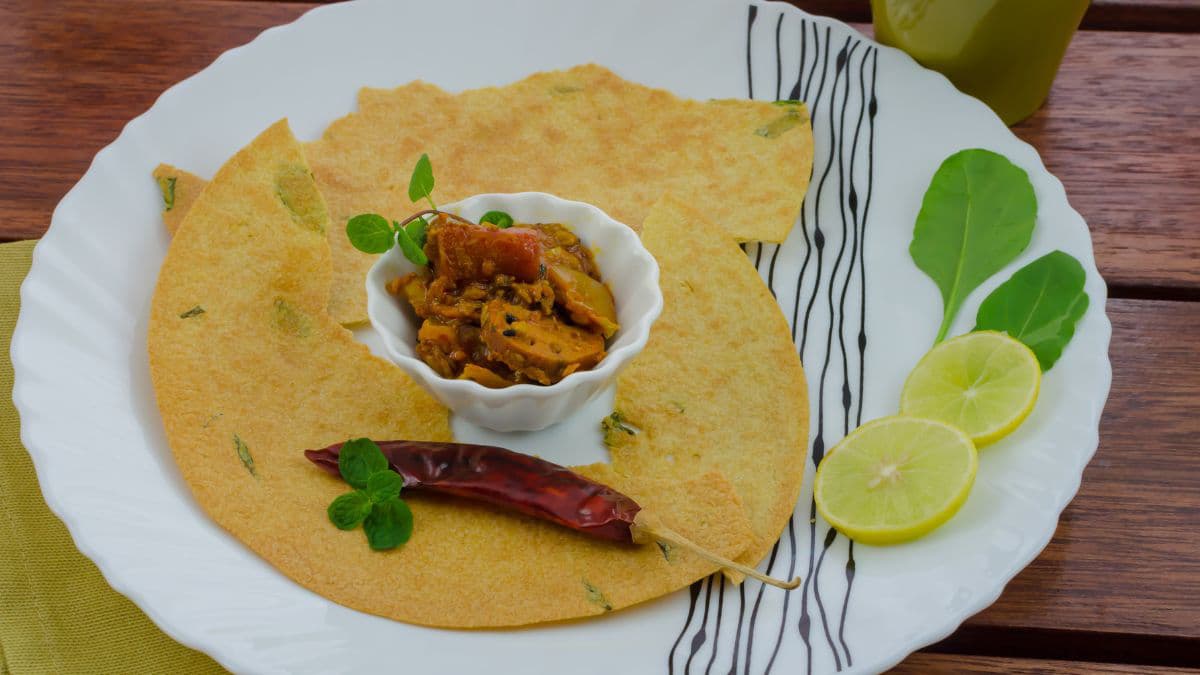 Khakra pieces around a small bowl of pickle