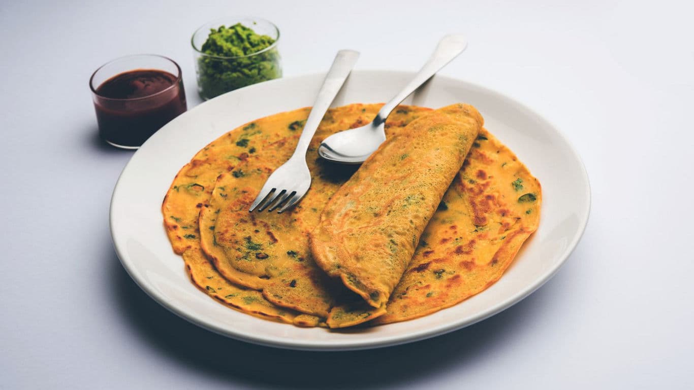 Indian savory pancakes with chutney and sauce sides