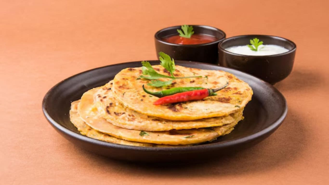 Stack of parathas with dips and chilies