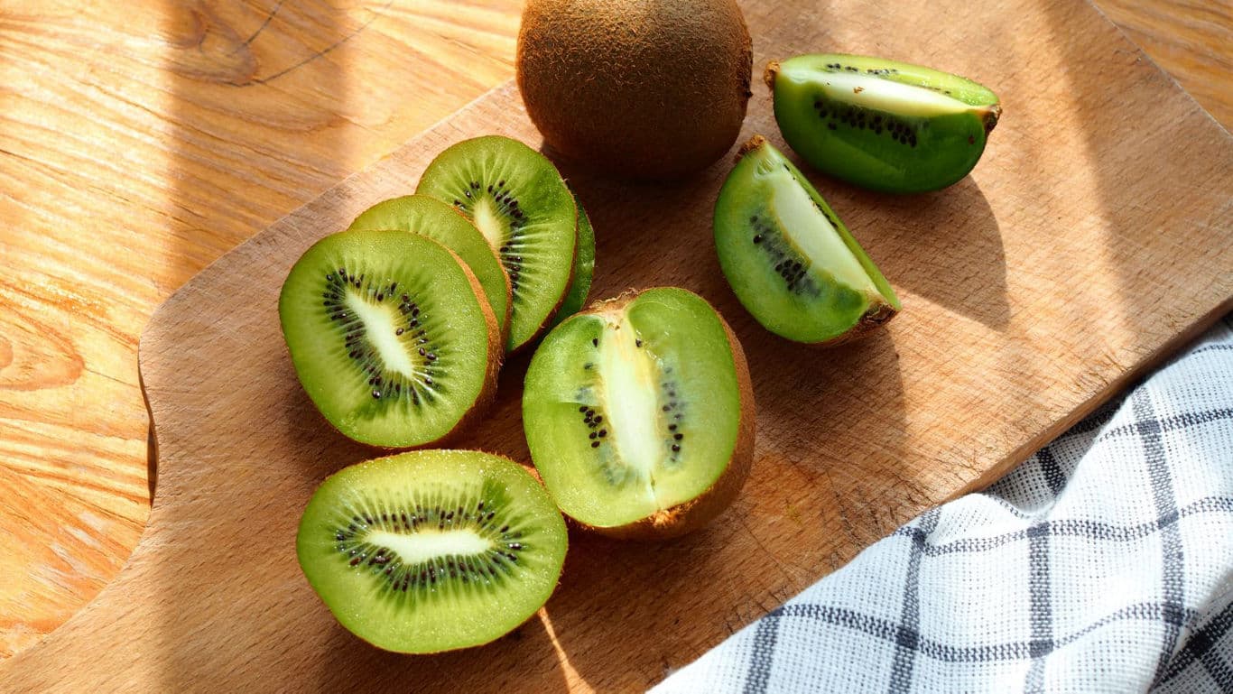 Fresh kiwi fruit halves on wooden cutting board