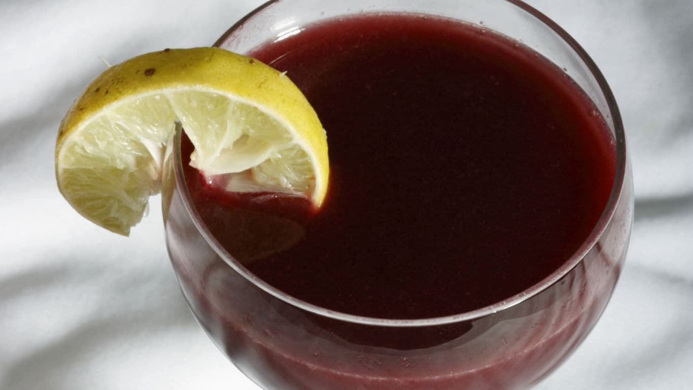 Glass of dark red drink with lemon