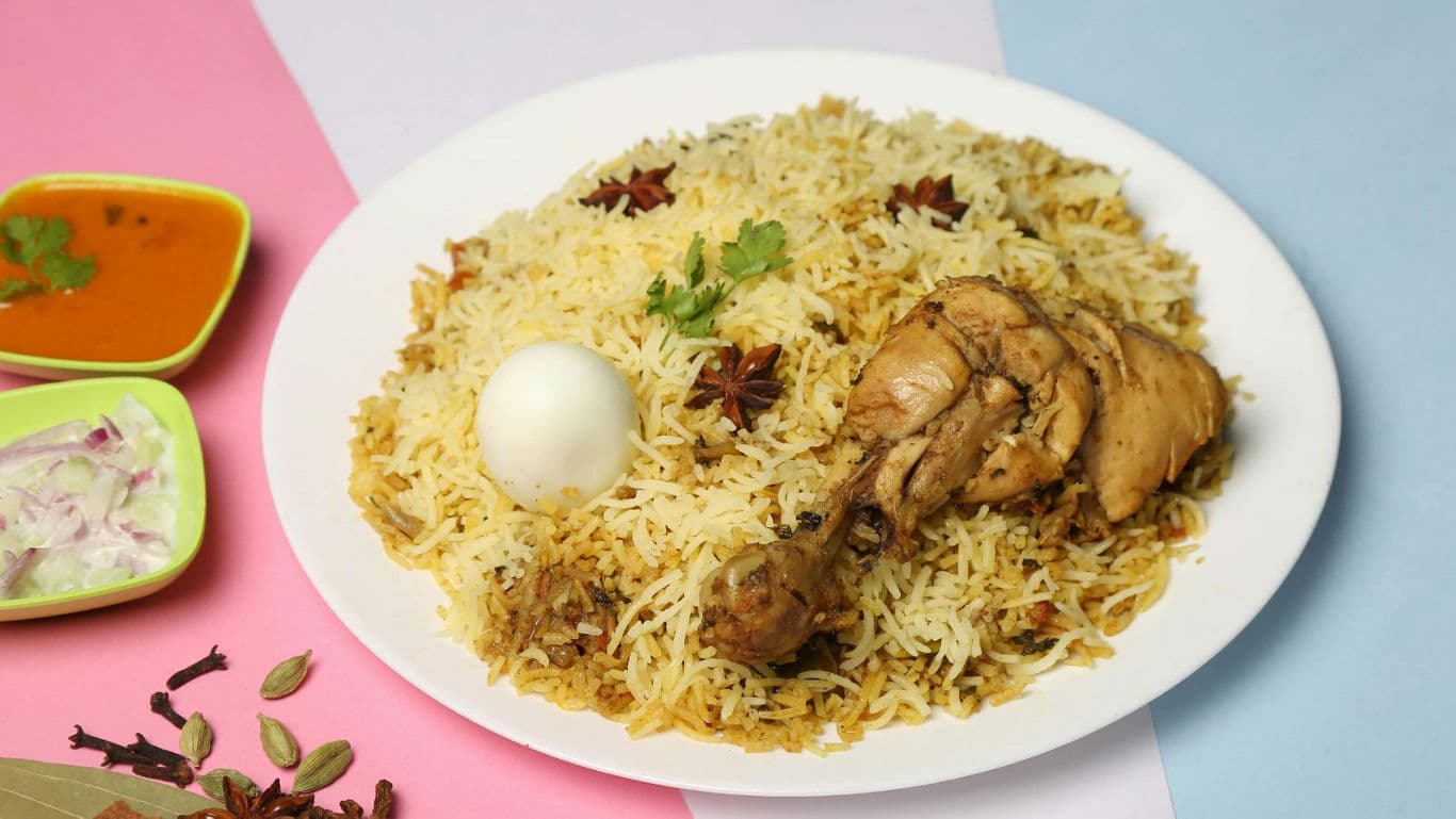 Chicken biryani with boiled egg and side dishes