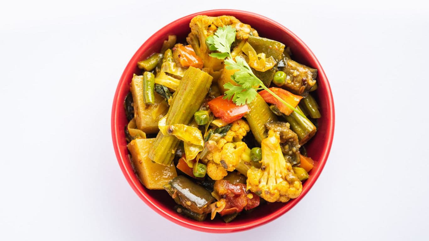 Colorful Indian mixed vegetable curry in red bowl
