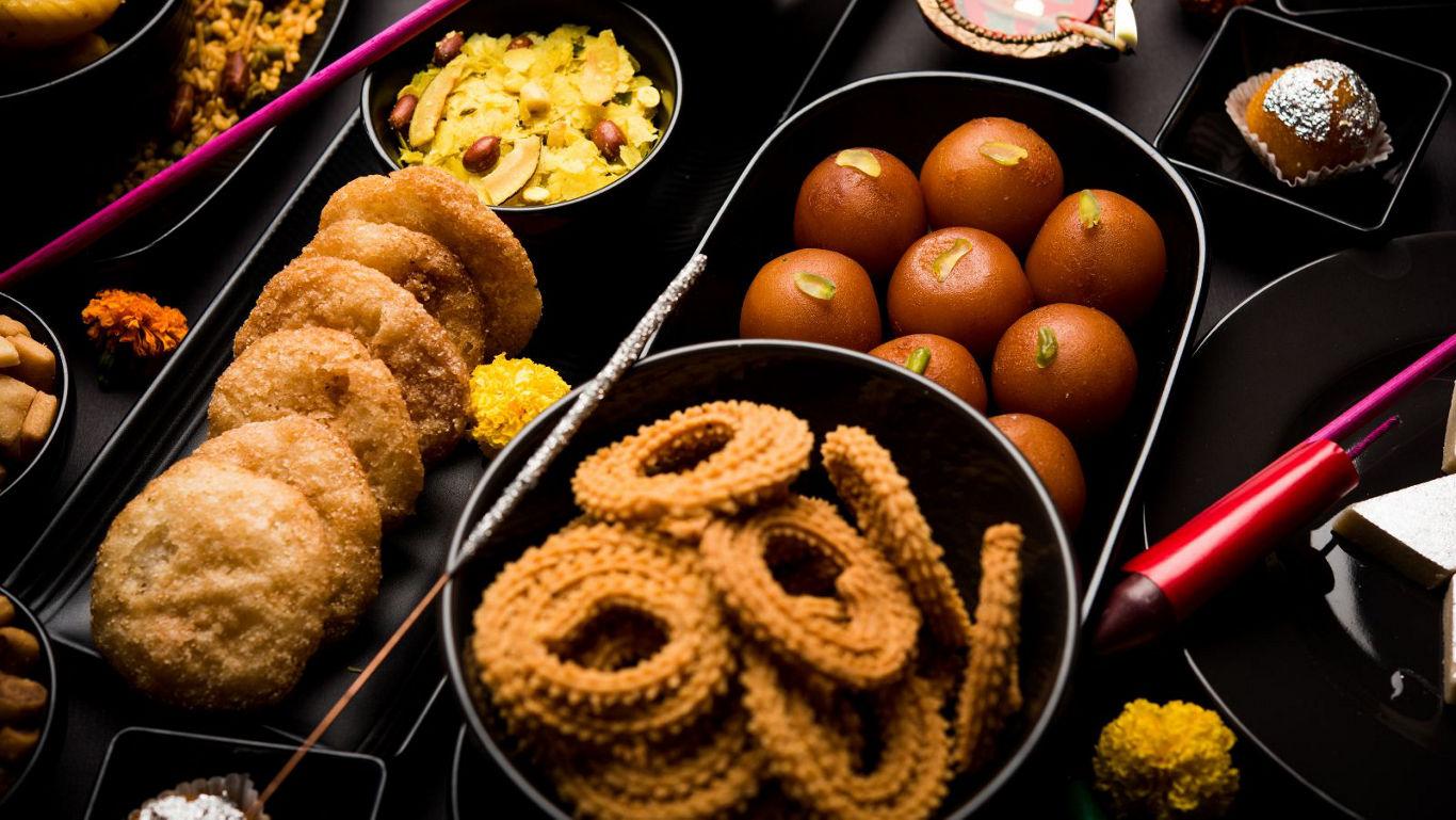 Assorted Indian sweets and snacks on black plates