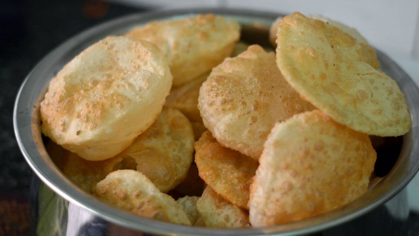 Crispy Indian puris served in a steel bowl