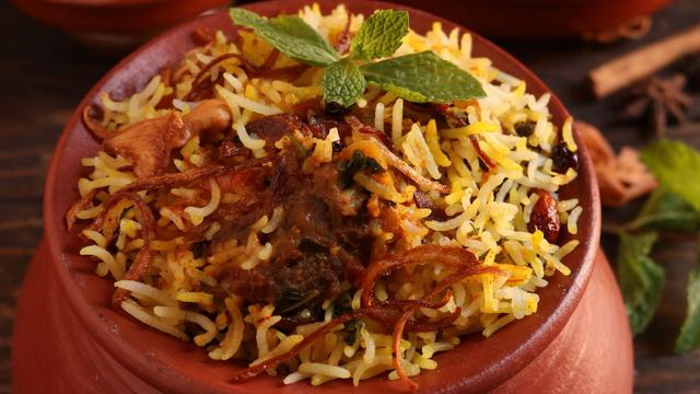 Aromatic Eid biryani served in a clay pot bowl with mint and fried onions on top.