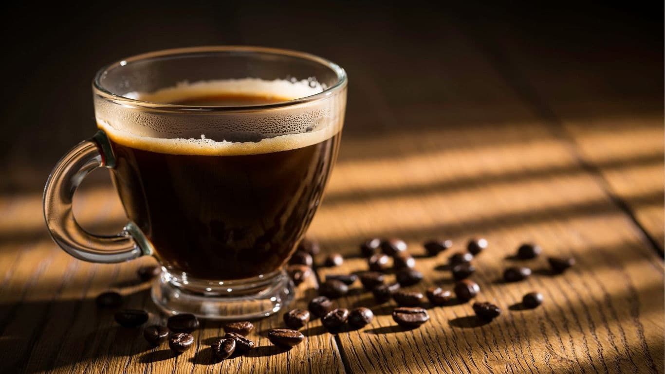 Glass cup of black coffee with beans