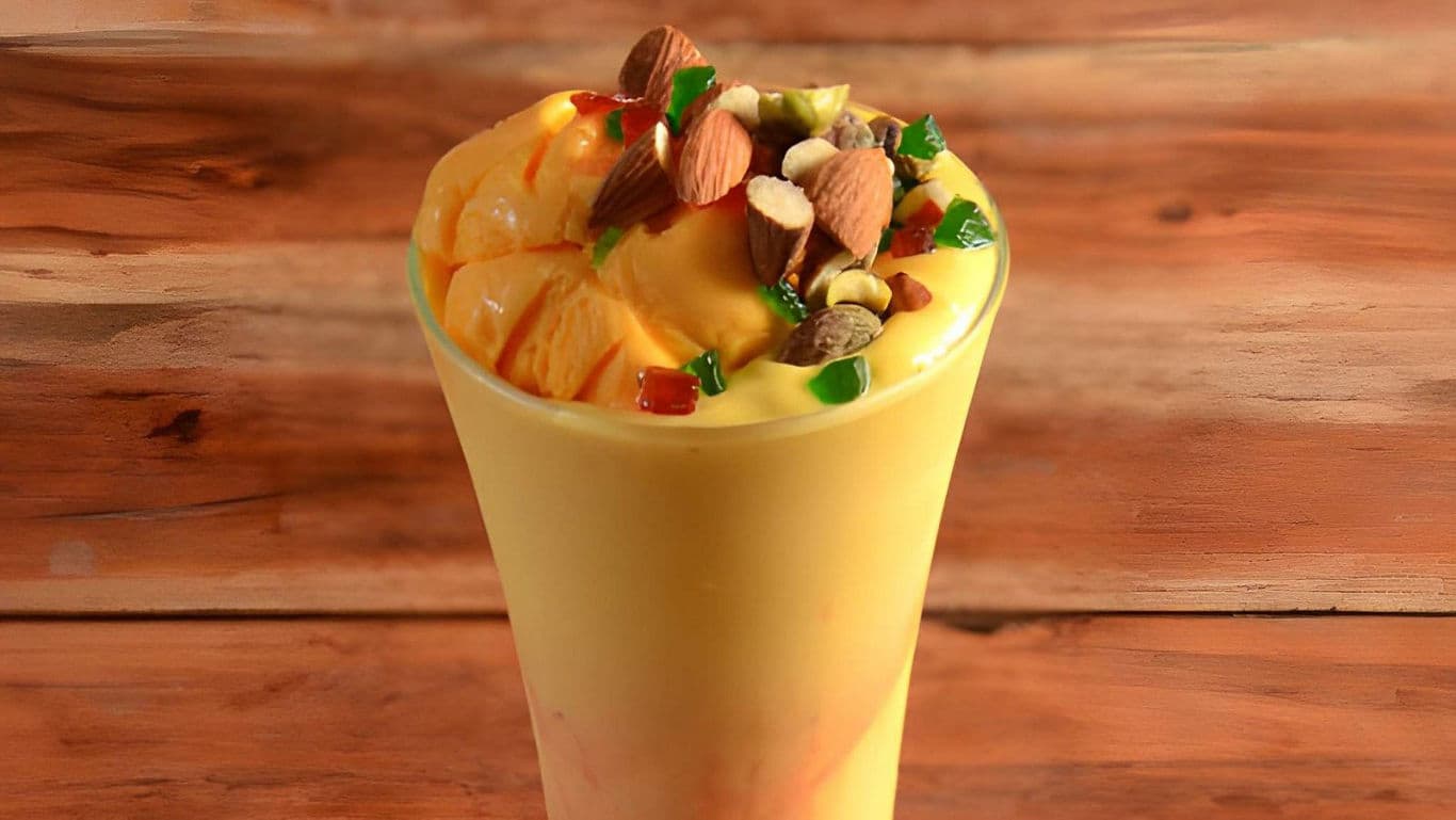 Mango smoothie topped with nuts and candied fruit