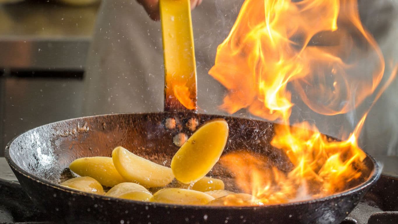 Potatoes flambéed in skillet with flames