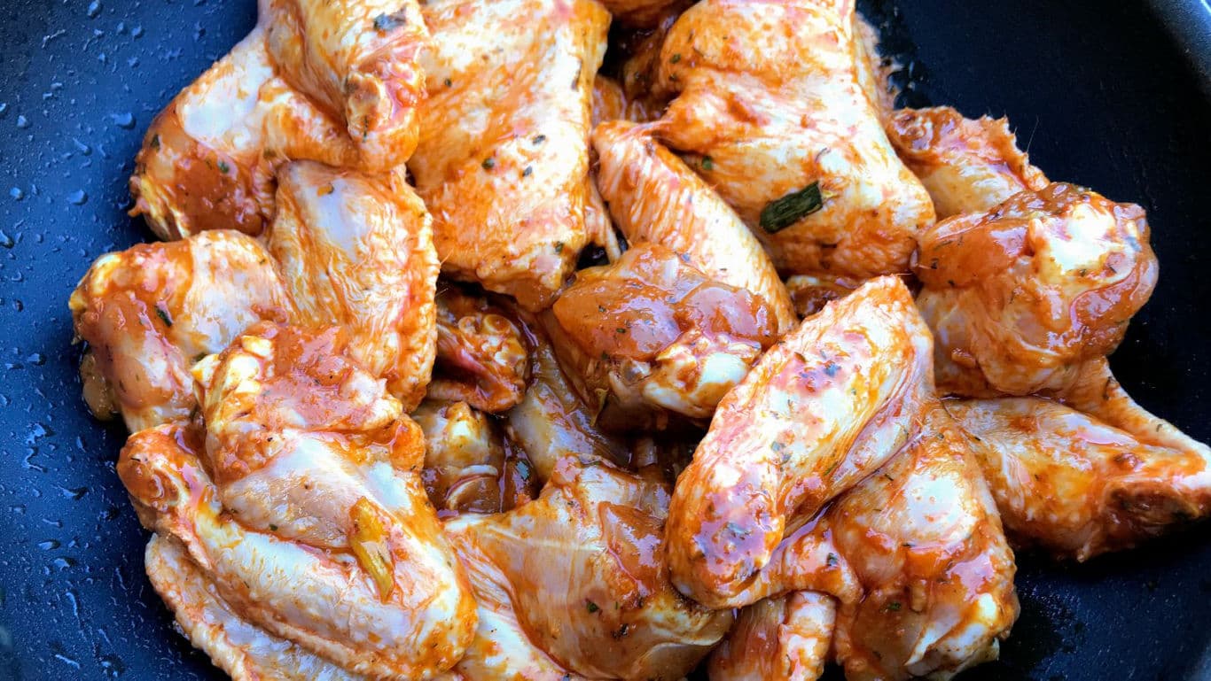 Raw marinated chicken wings in pan