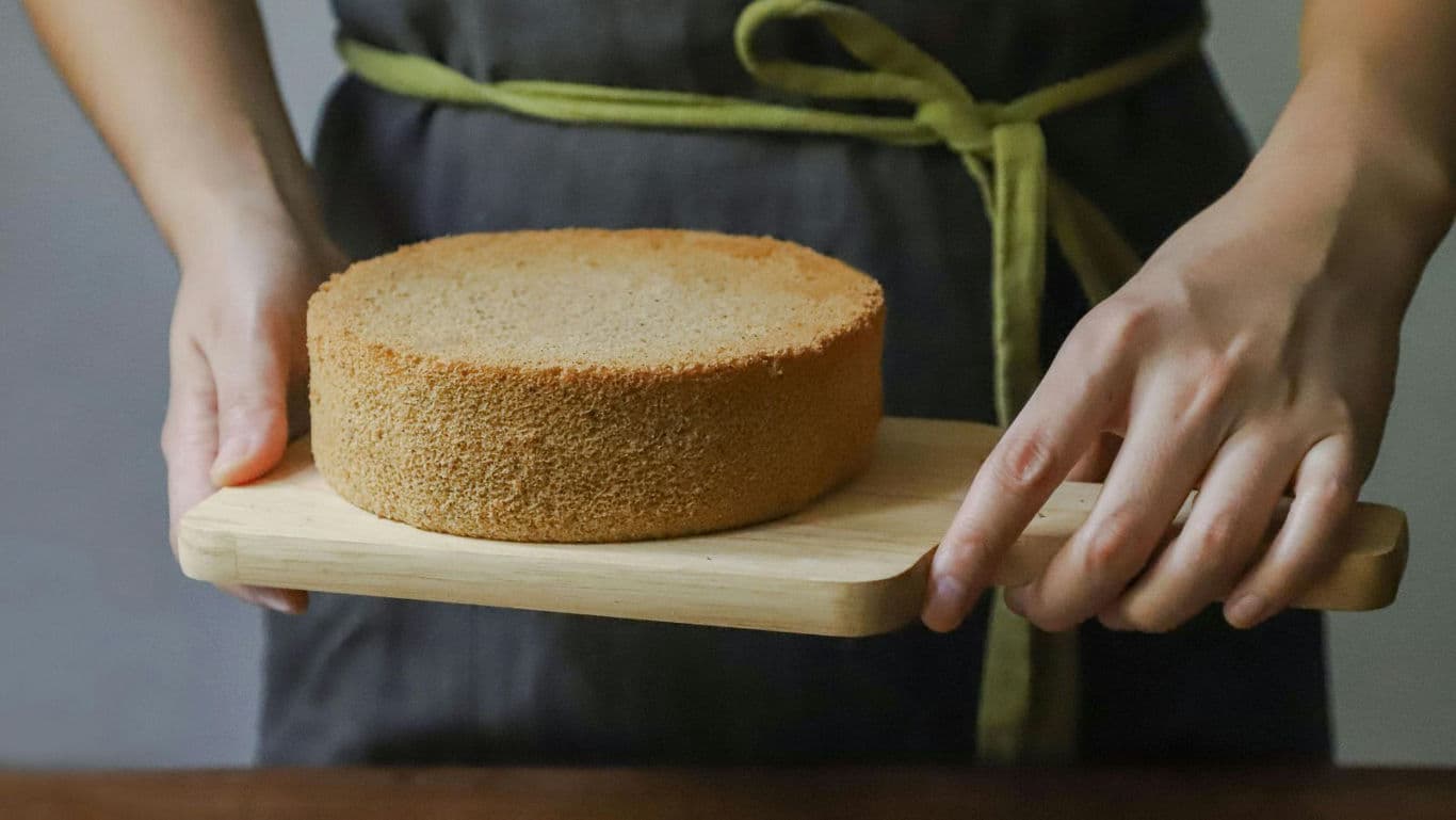 Baker presenting plain sponge cake on board