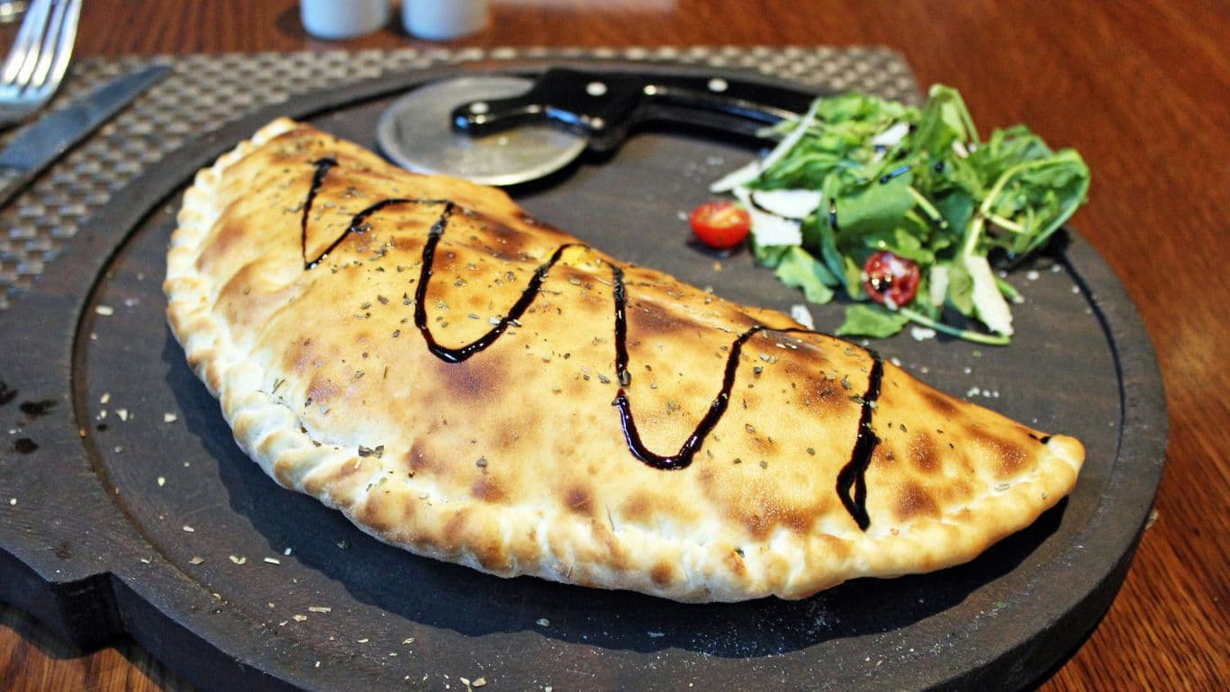 Baked calzone with salad on board