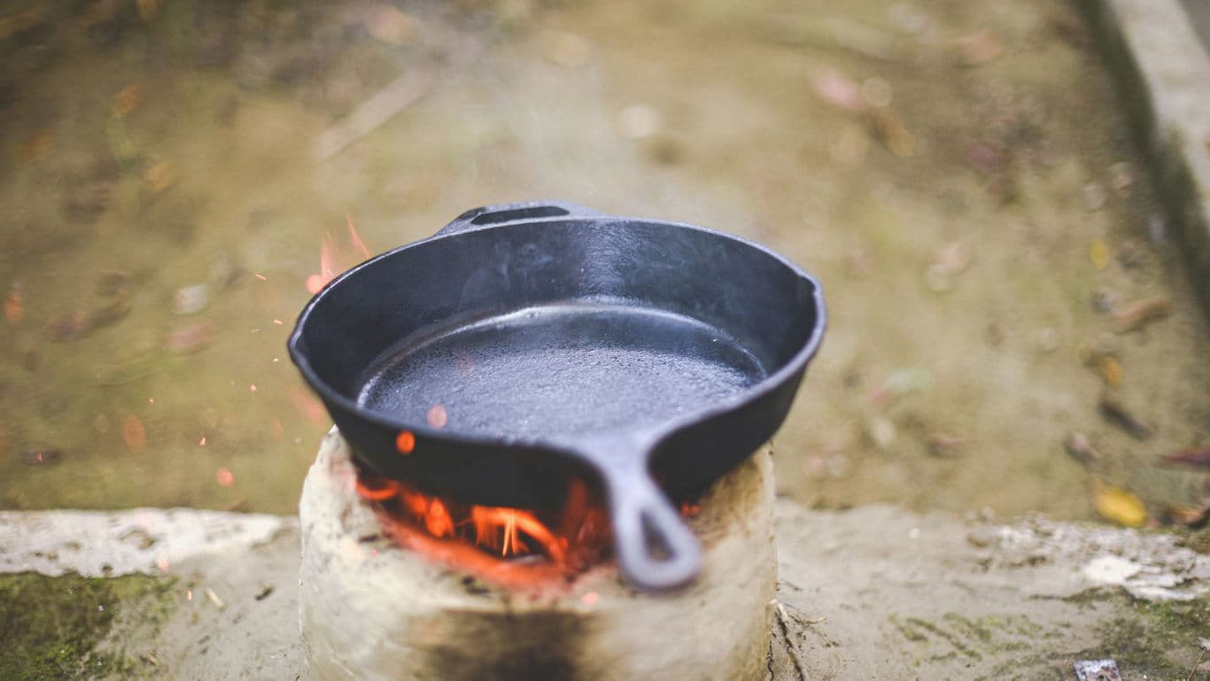 Cast iron skillet heating over outdoor fire
