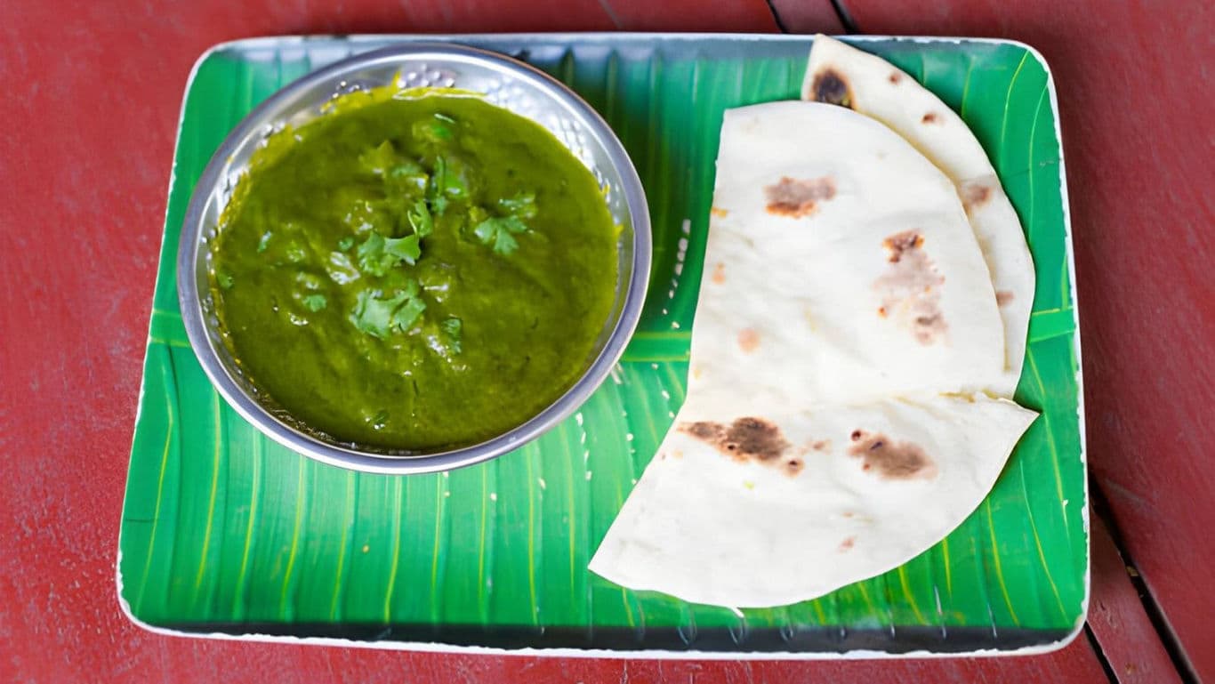 Indian flatbread with green curry on banana leaf plate