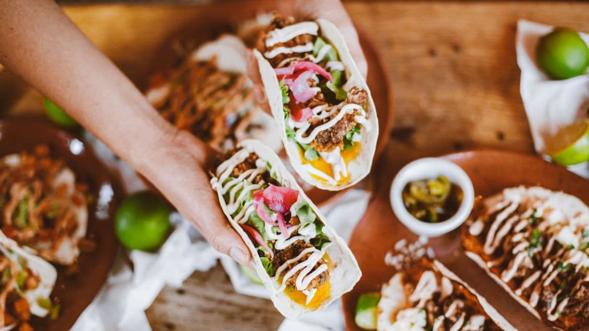 a man holding 2 tacos