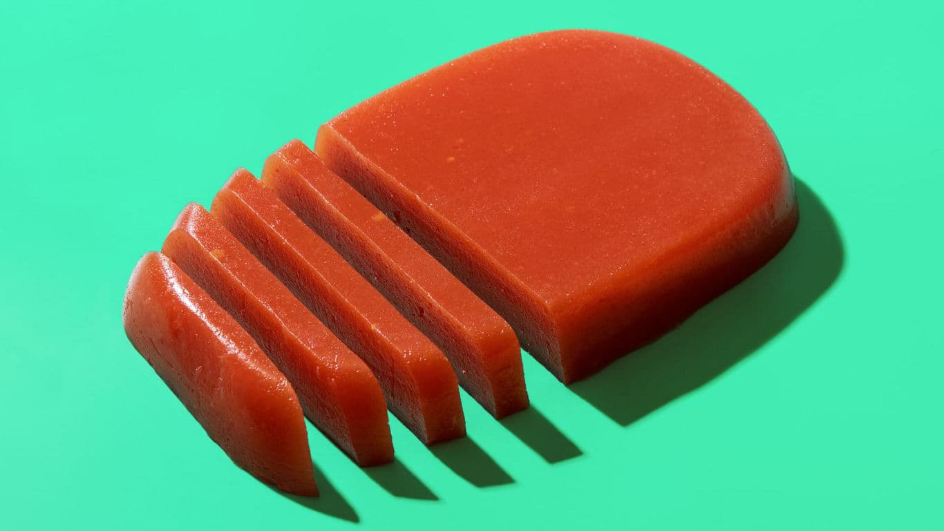 Sliced red fruit paste on green background